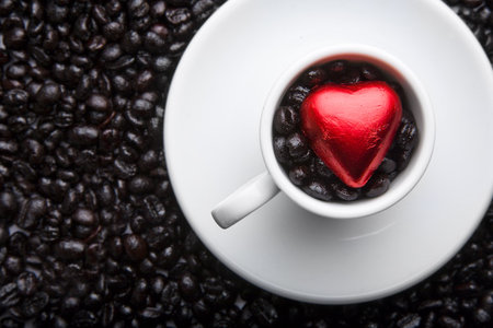 Coffee cup with black beans and red heartの写真素材