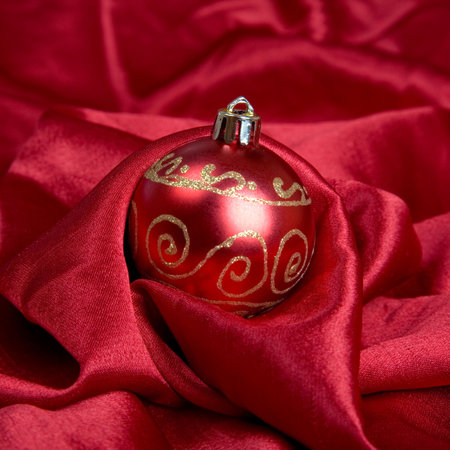 Red christmas bauble on red satinの写真素材