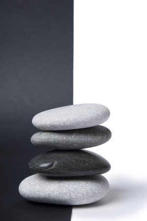 Black and white pebbles arranged in a stack with nice balance and a split black and white backgroundの写真素材