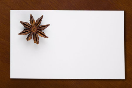 A blank white card with a star anise on a rich brown tableの写真素材