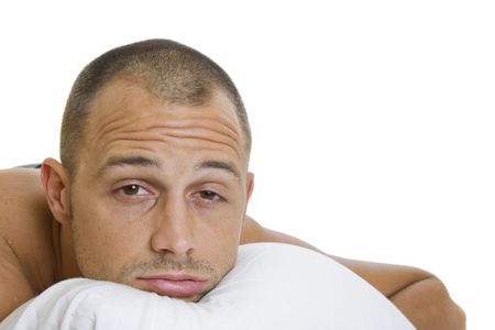 Man in bed trying to sleep with a pillow の写真素材