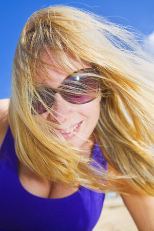 Smiling woman with blue sky and long blonde hairの写真素材