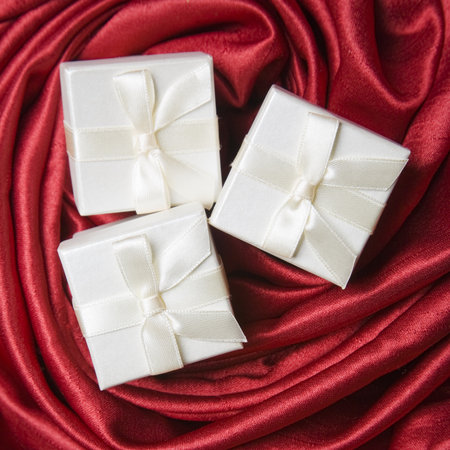 Three white gift boxers on a red silk backgroundの写真素材