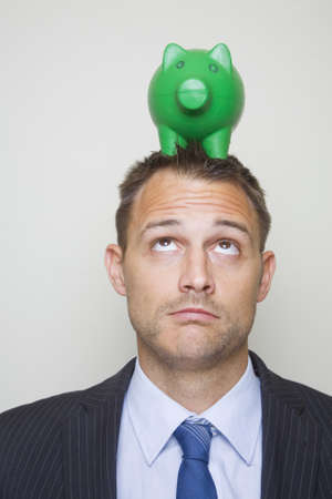 Businessman with a green piggy bank on his head.の写真素材