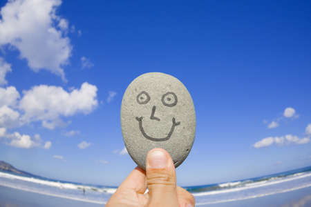 Wide angle shot of a smailing pebble in front of a sandy beach. の写真素材