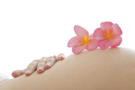 Close up of pregnant woman holding her tummy with exotic flowersの写真素材