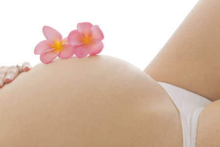 Close up of pregnant woman holding her tummy with exotic flowersの写真素材
