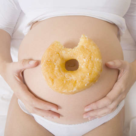 Pregnant woman with a doughnutの写真素材