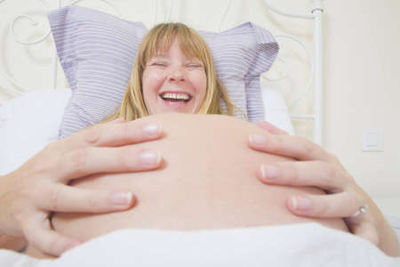 Pregnant woman smiling in bedの写真素材