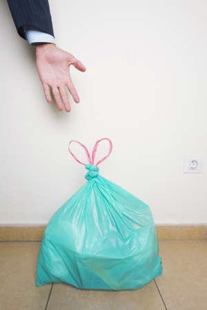Businessman reaching for a tgreen plastic bag with the ties forming a heart shapeの写真素材