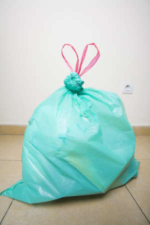 A green trash bag with red draw strings in a heart shape.の写真素材