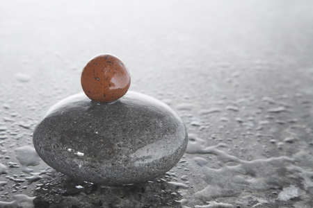 Stack of zen pebbles on a shiny, wet surfaceの写真素材