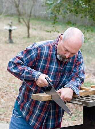 Man using small hand saw to cut boardの写真素材