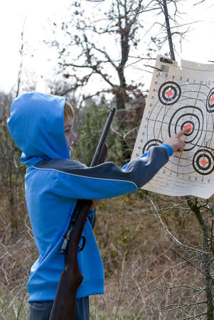 Boy checking his target while holding his rifleの写真素材