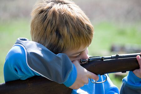Colse up of boy pulling trigger on rifleの写真素材
