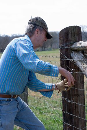 Man repairing fence with fence pliersの写真素材