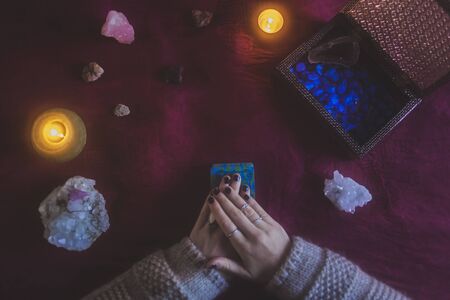 Young woman starting a tarot card reading with a mystical background of candles, stones and crystalsの写真素材
