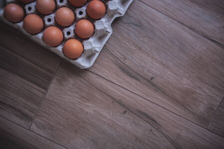 Rustic background of an egg carton in a corner on a wooden boardの写真素材