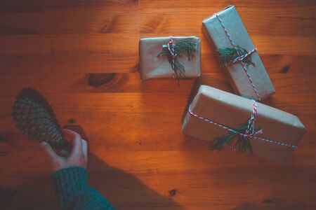 Young woman catching a pinecone while wrapping a gift with a rustic wooden background