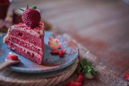 Red Velvet cake on a blue plate with strawberries and pure cocoa with a rustic background with flowers and cloth napkinsの写真素材