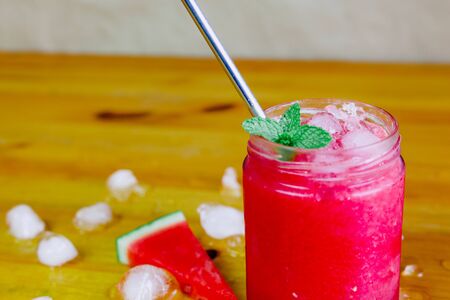 Close-up of a watermelon slush with an aluminum straw and watermelon triangles with ice and peppermintの写真素材