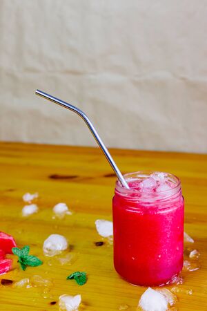 Watermelon slush with an aluminum straw and watermelon triangles with ice and peppermintの写真素材