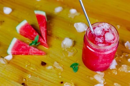 Watermelon slush with an aluminum straw and watermelon triangles with ice and peppermintの写真素材