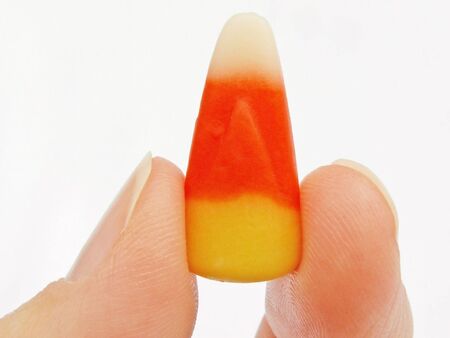 a candy corn held with fingertipsの写真素材
