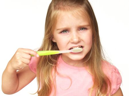 little girl brushing her teeth with a green toothbrush