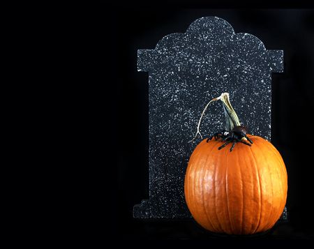 Halloween - orange pumpkin with a spider on top and tombstone behindの写真素材