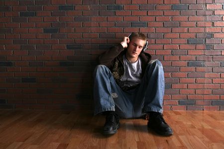grunge man in headphones next to brick wall and wood floorの写真素材