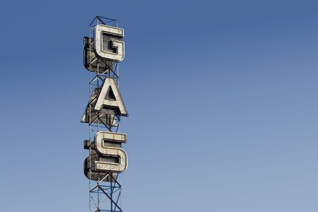 An industrial looking sign for a gas station against the blue sky.の写真素材