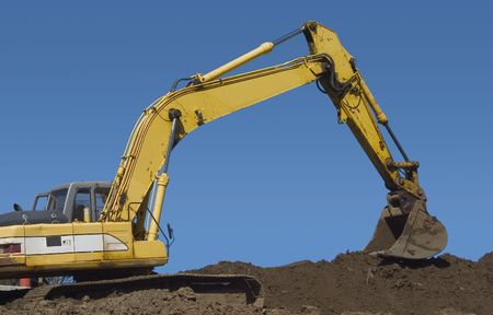 The claw of a backhoe works on a pile of dirt.