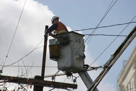 An electrician, high on a lift, works the wires.の写真素材