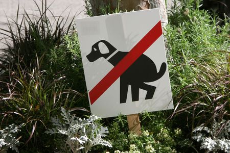 A sign warns dog owners to keep dogs from pooping in the flowers.の写真素材