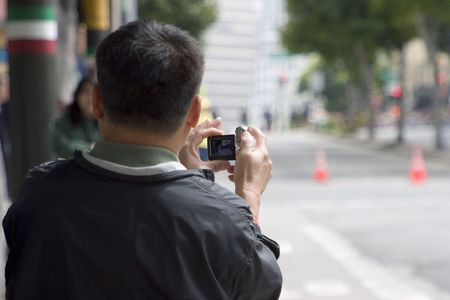 A tourist shoots some video of a city street.の写真素材