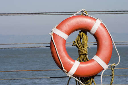 A bright orange lifesaver on the side of a ship.の写真素材