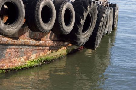 Old tires serve as bumpers for a tug boat.の写真素材