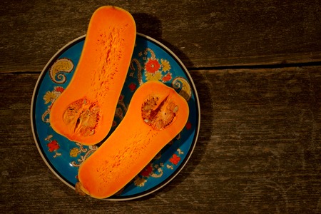 Cut ripe orange pumpkin with seeds on rustic wooden background. Vegetarian and raw organic healthy food concept, diet.の写真素材