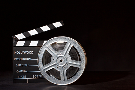 Clapperboard and film reel on the black backgroundの写真素材