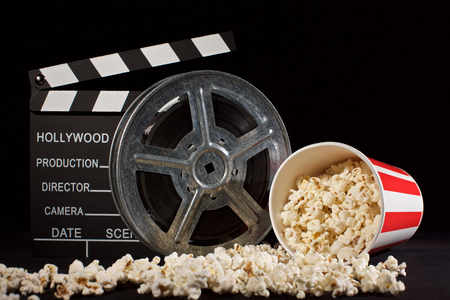 movie film reel and film clapper with popcorn box on blackの写真素材