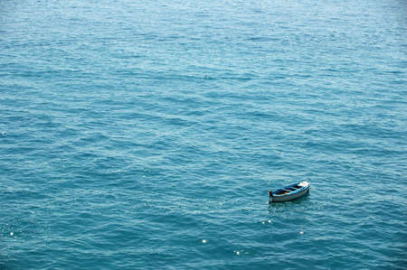 A lone boat sits empty in the middle of the sea.の写真素材