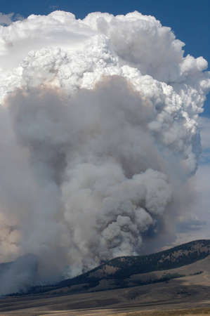 A fire burns up a hillside filling the sky with smoke.の写真素材