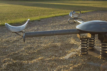 A seesaw in an empty playground just before sunset.の写真素材