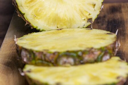 Ripe pineapple and pineapple slices on a wooden background tropical fruits.