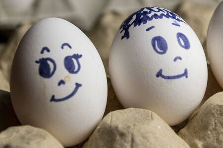 Lovely eggs in cardboard box. Eggs with emotions. White eggs in cardboard box with different faces...