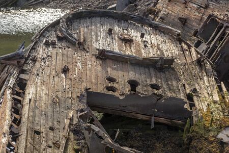 old shipwreck or abandoned shipwreck, broken fishing ship lies on its side near the shore