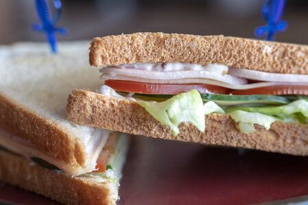 Close-up photo of a club sandwich. Sandwich with meet, prosciutto, salami, salad, vegetables,...