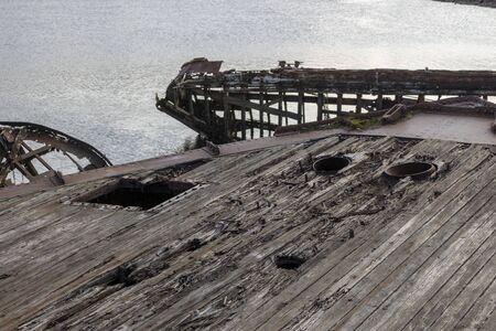 old shipwreck or abandoned shipwreck, broken fishing ship lies on its side near the shoreの写真素材