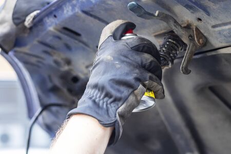 A man lubricates the hinges on the hood of a carの写真素材
